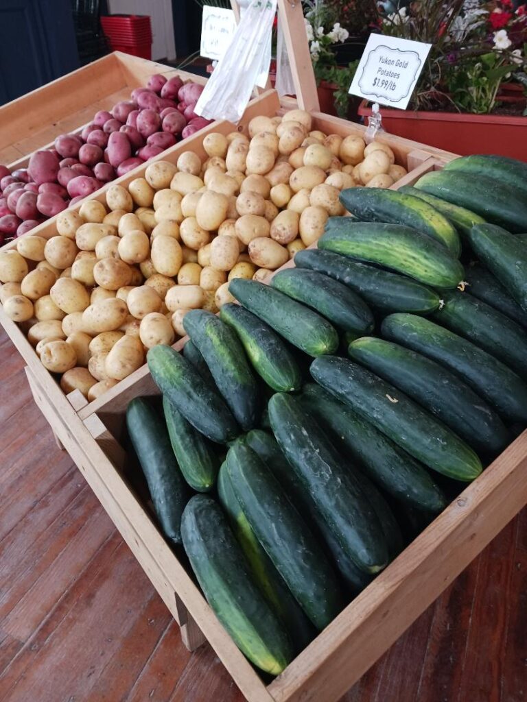 a wood rack with cucumbers and potatoes