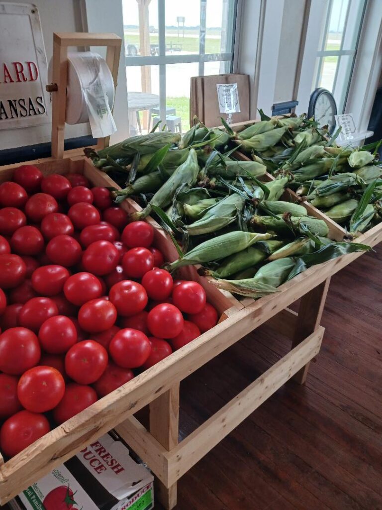 a wood rack with sweet corn and tomatoes